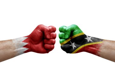 Two hands punch to each others on white background. Country flags painted fists, conflict crisis concept between bahrain and saint kitts and nevis