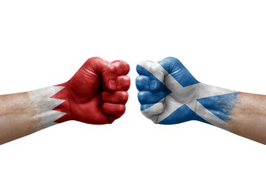 Two hands punch to each others on white background. Country flags painted fists, conflict crisis concept between bahrain and scotland