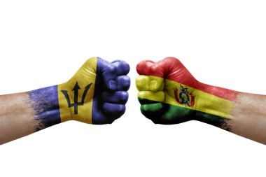 Two hands punch to each others on white background. Country flags painted fists, conflict crisis concept between barbados and bolivia