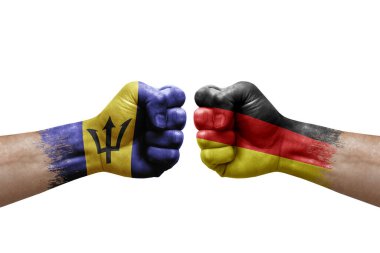 Two hands punch to each others on white background. Country flags painted fists, conflict crisis concept between barbados and germany