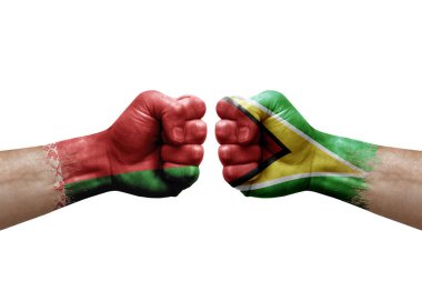 Two hands punch to each others on white background. Country flags painted fists, conflict crisis concept between belarus and guyana