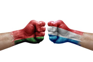 Two hands punch to each others on white background. Country flags painted fists, conflict crisis concept between belarus and luxembourg