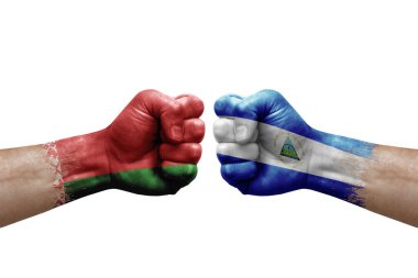 Two hands punch to each others on white background. Country flags painted fists, conflict crisis concept between belarus and nicaragua