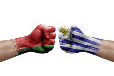 Two hands punch to each others on white background. Country flags painted fists, conflict crisis concept between belarus and uruguay