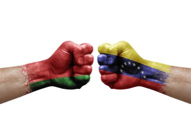 Two hands punch to each others on white background. Country flags painted fists, conflict crisis concept between belarus and venezuela