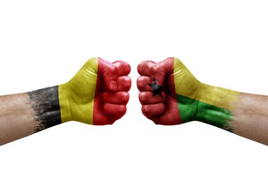 Two hands punch to each others on white background. Country flags painted fists, conflict crisis concept between belgium and guinea-bissau