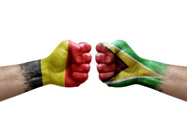 Two hands punch to each others on white background. Country flags painted fists, conflict crisis concept between belgium and guyana