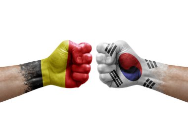Two hands punch to each others on white background. Country flags painted fists, conflict crisis concept between belgium and south korea