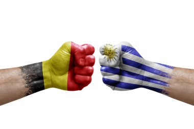 Two hands punch to each others on white background. Country flags painted fists, conflict crisis concept between belgium and uruguay