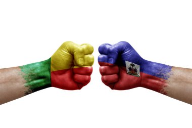 Two hands punch to each others on white background. Country flags painted fists, conflict crisis concept between benin and haiti
