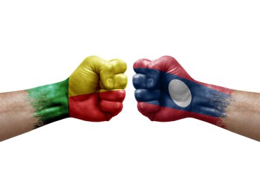 Two hands punch to each others on white background. Country flags painted fists, conflict crisis concept between benin and laos