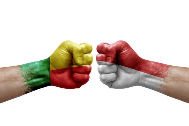 Two hands punch to each others on white background. Country flags painted fists, conflict crisis concept between benin and monaco