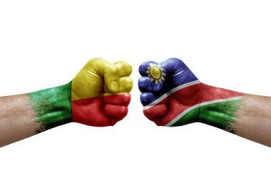 Two hands punch to each others on white background. Country flags painted fists, conflict crisis concept between benin and namibia