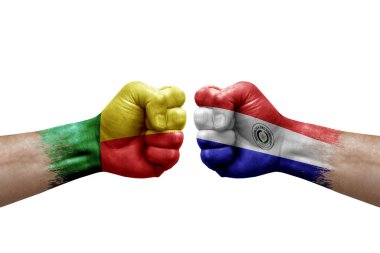 Two hands punch to each others on white background. Country flags painted fists, conflict crisis concept between benin and paraguay