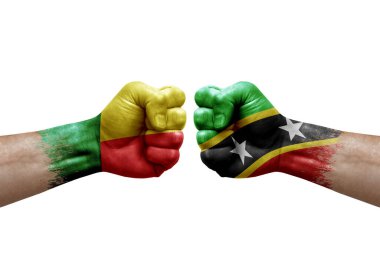 Two hands punch to each others on white background. Country flags painted fists, conflict crisis concept between benin and saint kitts and nevis