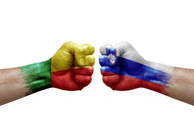 Two hands punch to each others on white background. Country flags painted fists, conflict crisis concept between benin and slovenia