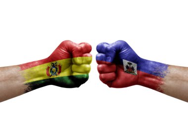Two hands punch to each others on white background. Country flags painted fists, conflict crisis concept between bolivia and haiti