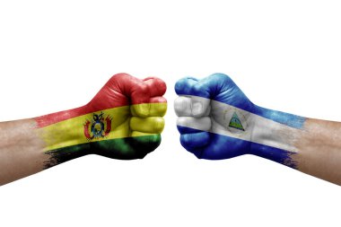 Two hands punch to each others on white background. Country flags painted fists, conflict crisis concept between bolivia and nicaragua