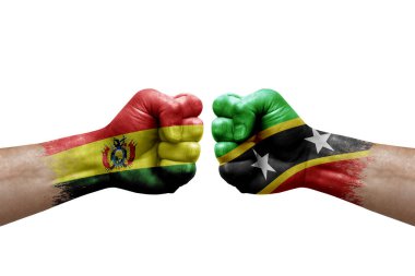 Two hands punch to each others on white background. Country flags painted fists, conflict crisis concept between bolivia and saint kitts and nevis