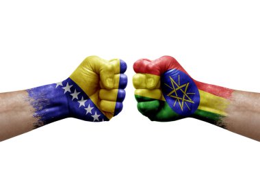 Two hands punch to each others on white background. Country flags painted fists, conflict crisis concept between bosnia and ethiopia