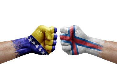 Two hands punch to each others on white background. Country flags painted fists, conflict crisis concept between bosnia and faroe islands
