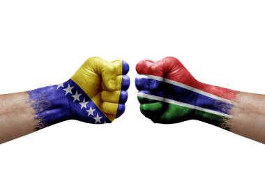 Two hands punch to each others on white background. Country flags painted fists, conflict crisis concept between bosnia and gambia