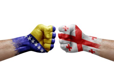 Two hands punch to each others on white background. Country flags painted fists, conflict crisis concept between bosnia and georgia