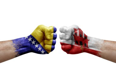 Two hands punch to each others on white background. Country flags painted fists, conflict crisis concept between bosnia and gibraltar