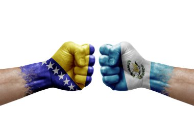 Two hands punch to each others on white background. Country flags painted fists, conflict crisis concept between bosnia and guatemala