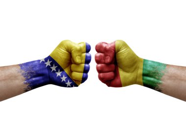 Two hands punch to each others on white background. Country flags painted fists, conflict crisis concept between bosnia and guinea