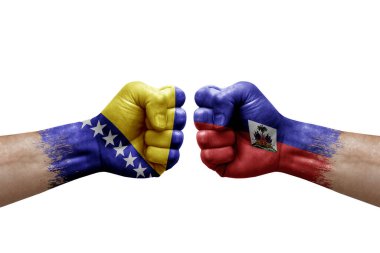 Two hands punch to each others on white background. Country flags painted fists, conflict crisis concept between bosnia and haiti