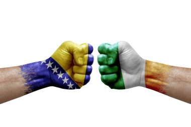 Two hands punch to each others on white background. Country flags painted fists, conflict crisis concept between bosnia and ireland