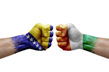 Two hands punch to each others on white background. Country flags painted fists, conflict crisis concept between bosnia and ivory coast