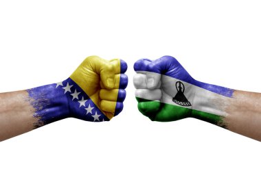 Two hands punch to each others on white background. Country flags painted fists, conflict crisis concept between bosnia and lesotho