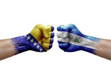Two hands punch to each others on white background. Country flags painted fists, conflict crisis concept between bosnia and nicaragua