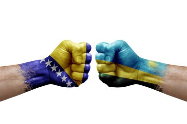 Two hands punch to each others on white background. Country flags painted fists, conflict crisis concept between bosnia and rwanda