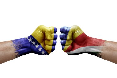 Two hands punch to each others on white background. Country flags painted fists, conflict crisis concept between bosnia and seychelles