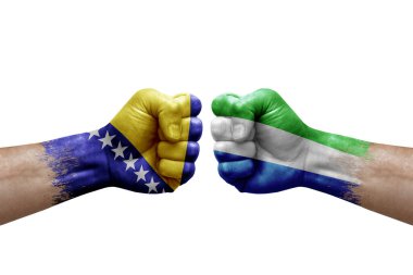 Two hands punch to each others on white background. Country flags painted fists, conflict crisis concept between bosnia and sierra leone