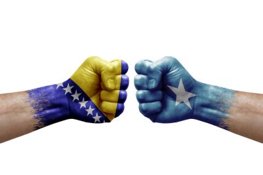 Two hands punch to each others on white background. Country flags painted fists, conflict crisis concept between bosnia and somalia