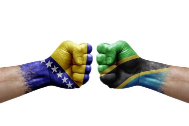 Two hands punch to each others on white background. Country flags painted fists, conflict crisis concept between bosnia and tanzania