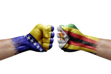 Two hands punch to each others on white background. Country flags painted fists, conflict crisis concept between bosnia and zimbabwe