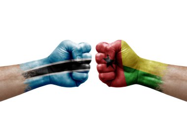 Two hands punch to each others on white background. Country flags painted fists, conflict crisis concept between botswana and guinea-bissau