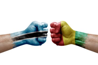 Two hands punch to each others on white background. Country flags painted fists, conflict crisis concept between botswana and guinea