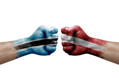 Two hands punch to each others on white background. Country flags painted fists, conflict crisis concept between botswana and latvia
