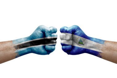 Two hands punch to each others on white background. Country flags painted fists, conflict crisis concept between botswana and nicaragua