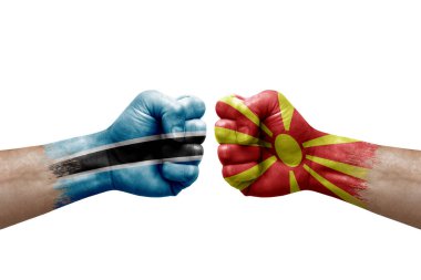Two hands punch to each others on white background. Country flags painted fists, conflict crisis concept between botswana and north macedonia