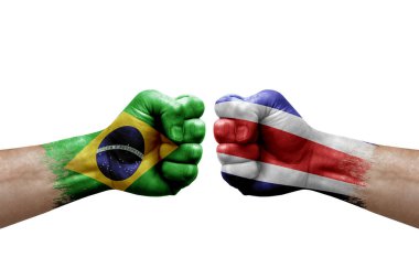 Two hands punch to each others on white background. Country flags painted fists, conflict crisis concept between brazil and costa rica