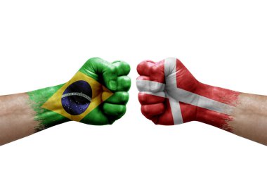 Two hands punch to each others on white background. Country flags painted fists, conflict crisis concept between brazil and denmark