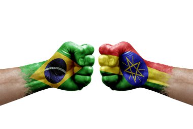 Two hands punch to each others on white background. Country flags painted fists, conflict crisis concept between brazil and ethiopia
