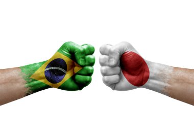 Two hands punch to each others on white background. Country flags painted fists, conflict crisis concept between brazil and japan
